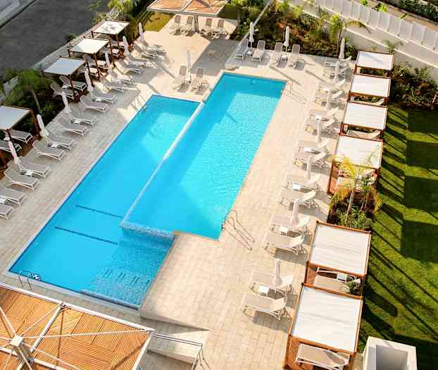 Näkymä ulkouima-altaalle, jota ympäröivät aurinkotuolit ja varjostavat pergolat. (Tekoälyn luoma teksti)