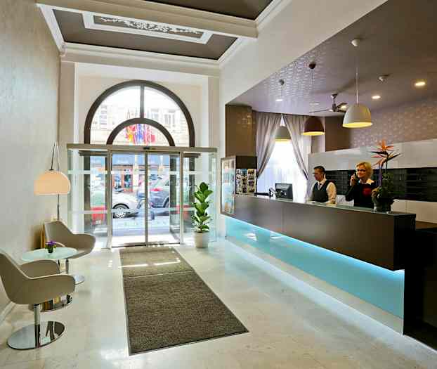 Hotellin aula, vastaanotto, istuma-alue ja lasiovet ulos. (Tekoälyn luoma teksti)