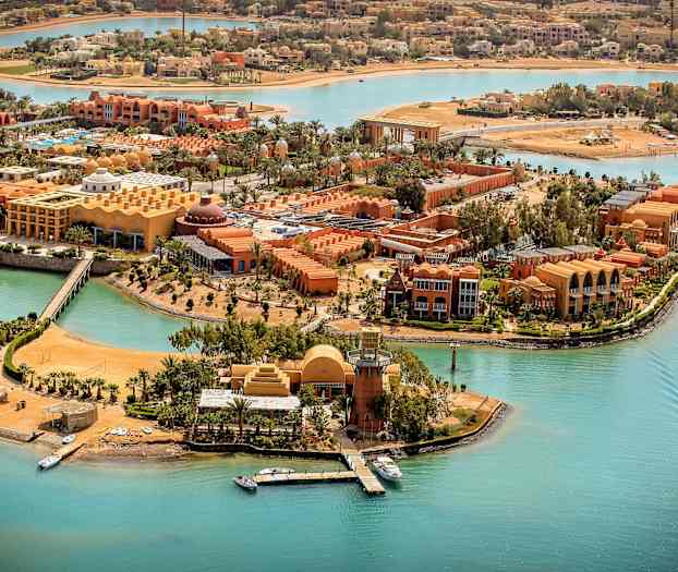 Ilmakuva lomakeskuksesta turkoosien kanavien äärellä, veneitä ja palmuja. (Tekoälyn luoma teksti)