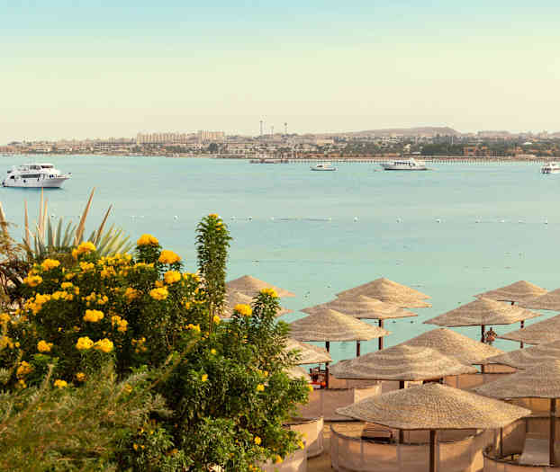 Ranta varjoineen, meri ja veneitä taustalla. (Tekoälyn luoma teksti)