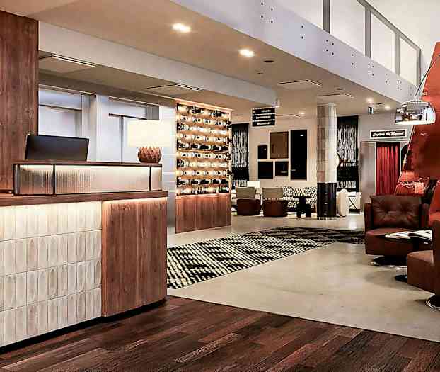 Hotellin aula, jossa vastaanottotiski, istuimet ja koristevalaistus. (Tekoälyn luoma teksti)