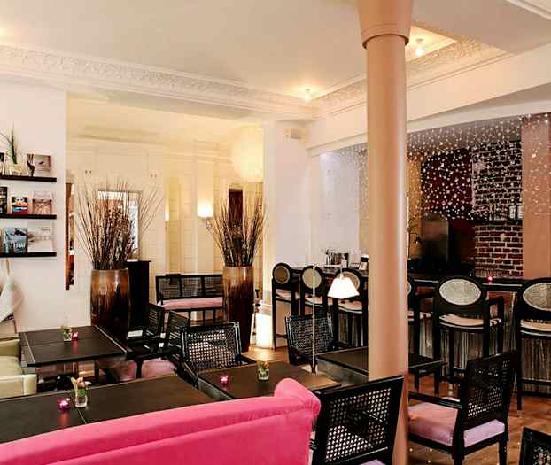 Sisustettu kahvila- tai hotellitila, jossa pöytiä, tuoleja ja koristeita. (Tekoälyn luoma teksti)