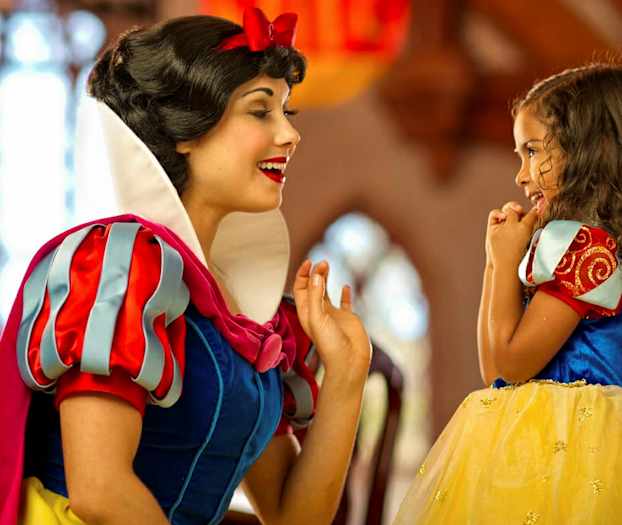 Kaksi henkilöä on pukeutunut Lumikkiin ja prinsessaan värikkäässä ympäristössä. (Tekoälyn luoma teksti)