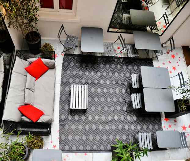 Sisäpihan ympäristö, jossa istumapaikkoja ja harmaa sisustus. (Tekoälyn luoma teksti)