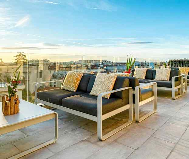 Kalustettu kattoterassi, josta on näkymä kaupunkiin ja auringonlaskuun. (Tekoälyn luoma teksti)