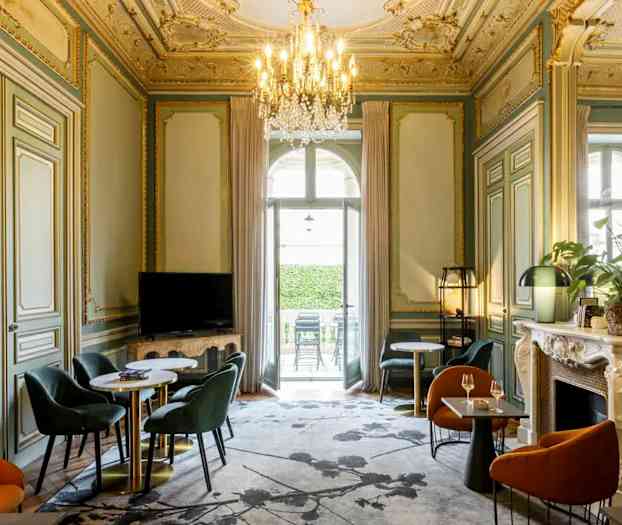 Tyylikkäästi sisustettu huone, jossa on koristeellinen katto, istuinryhmiä ja kattokruunu. (Tekoälyn luoma teksti)