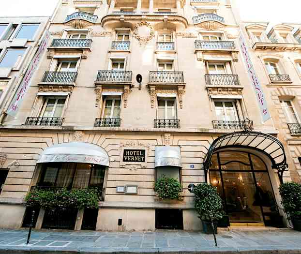 Hotelli Vernet, klassinen kivitalo, jossa koristeellinen julkisivu ja parvekkeet sekä lasiovellinen pääsisäänkäynti ja katos. (Tekoälyn luoma teksti)