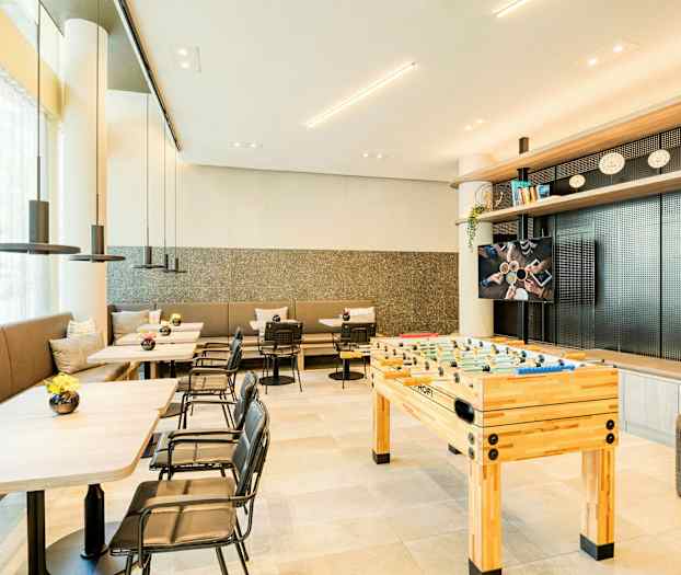 Moderni huone, jossa pöytiä, tuoleja ja pöytäjalkapallopöytä. (Tekoälyn luoma teksti)