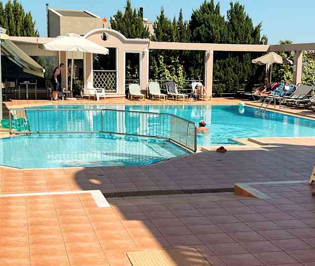 Ulkouima-allas, jonka reunalla aurinkotuoleja ja aurinkovarjoja sekä ihmisiä uimassa ja paistattelemassa. (Tekoälyn luoma teksti)