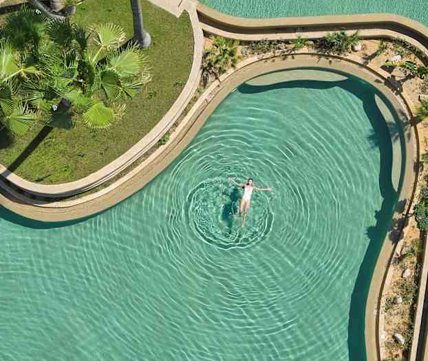 Henkilö kelluu altaassa vihreän ympäristön keskellä. (Tekoälyn luoma teksti)