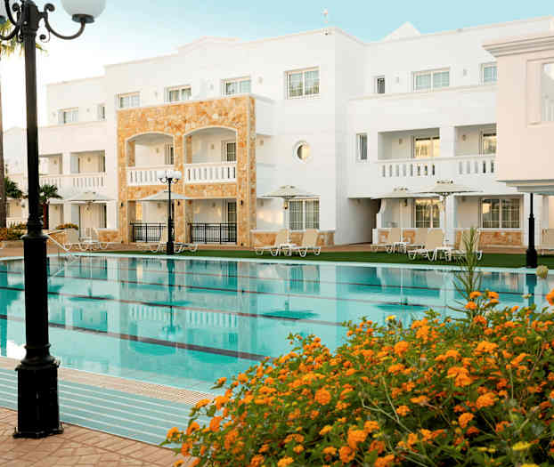 Hotellirakennus uima-altaalla ja ympärillä olevilla aurinkotuoleilla. (Tekoälyn luoma teksti)