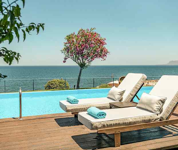 Kaksi aurinkotuolia uima-altaan äärellä, näkymä merelle. (Tekoälyn luoma teksti)
