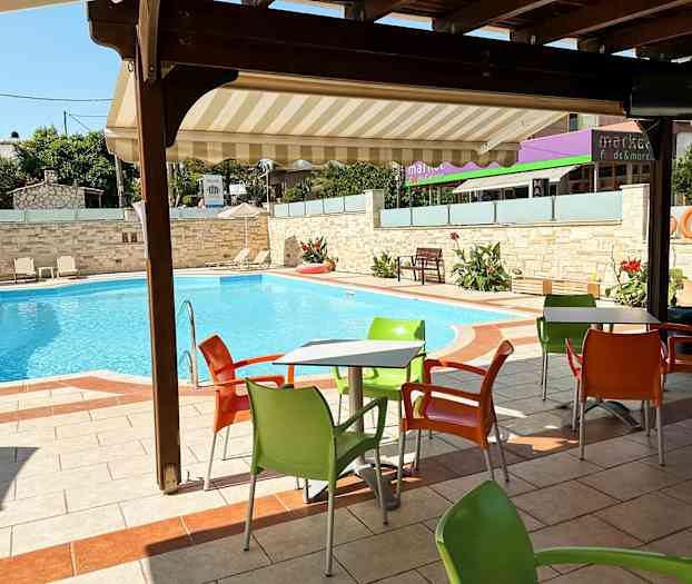 Ulkoilmassa pöytä, jossa värikkäitä tuoleja uima-altaan äärellä. (Tekoälyn luoma teksti)