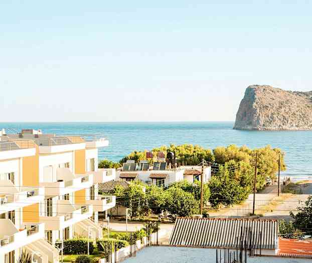 Näkymä rakennuksista, vehreydestä ja merestä, taustalla kallio. (Tekoälyn luoma teksti)