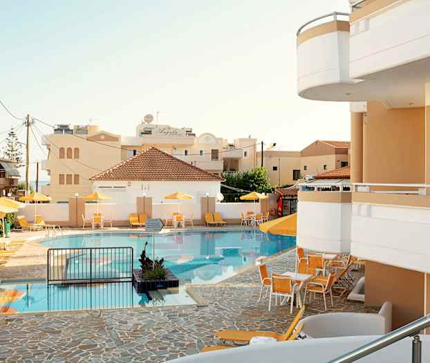 Uima-allas, jossa on aurinkotuoleja ja aurinkovarjoja hotellin vieressä. (Tekoälyn luoma teksti)