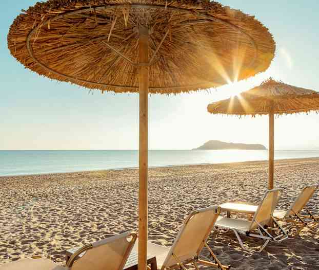 Aurinkotuoleja hiekkarannalla varjojen alla. (Tekoälyn luoma teksti)