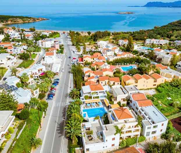 Ilmakuva rannikkokaupungista, jossa on taloja, uima-altaita ja meri taustalla. (Tekoälyn luoma teksti)