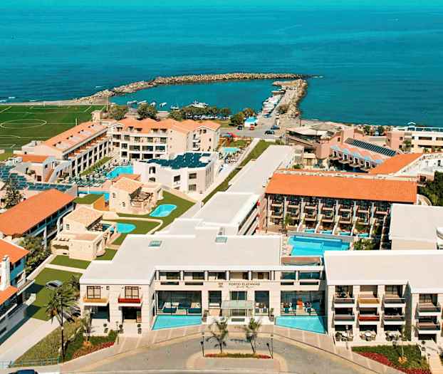 Ilmakuva hotellialueesta rannikolla, jossa on uima-altaita, rakennuksia ja meri taustalla. (Tekoälyn luoma teksti)