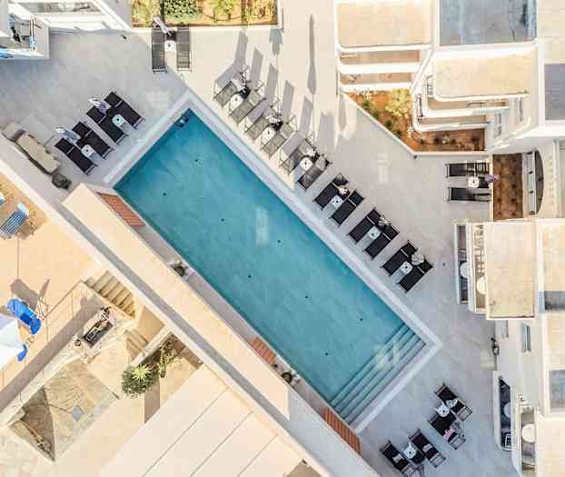 Ilmakuva ulkouima-altaasta, jota ympäröivät aurinkotuolit ja pöydät. (Tekoälyn luoma teksti)