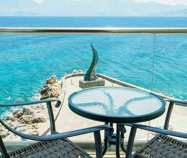 Näkymä terassilta merelle, etualalla kaksi tuolia ja pöytä. (Tekoälyn luoma teksti)