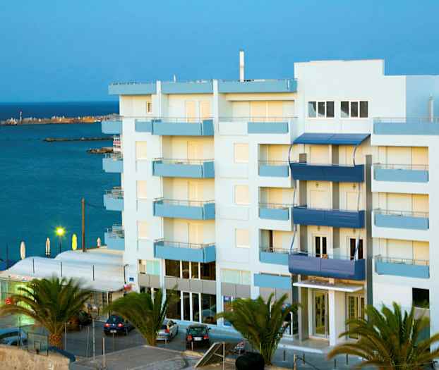 Kerrostalo meren läheisyydessä, ympäröitynä palmuilla. (Tekoälyn luoma teksti)