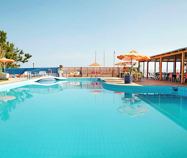 Ulkouima-allas, jonka vieressä on aurinkovarjoja ja pöytiä. (Tekoälyn luoma teksti)