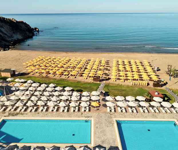 Näkymä allasalueelta aurinkotuolien ja aurinkovarjojen äärellä rannalla. (Tekoälyn luoma teksti)