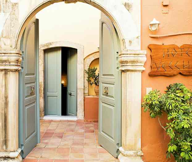 Kuvassa on sisäänkäynti kaarineen, avoimet pariovet, kyltti 'Hotel Vecchio' ja ympärillä kasvillisuutta. (Tekoälyn luoma teksti)