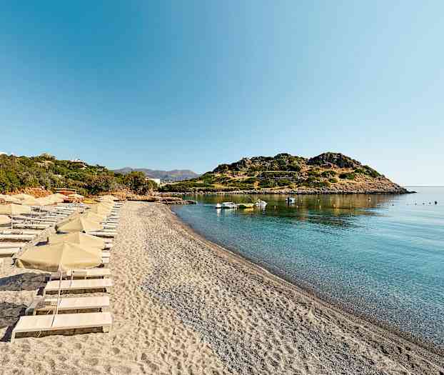 Ranta aurinkotuoleilla ja -varjoilla rauhallisen lahden äärellä. (Tekoälyn luoma teksti)