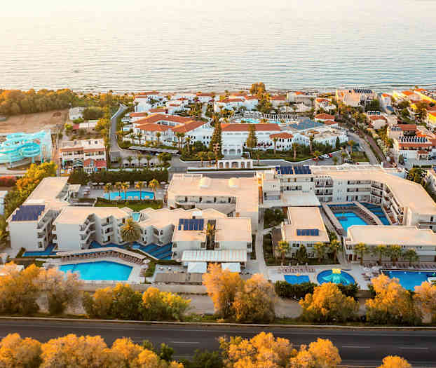 Lentokuva lomahotellista, jossa on useita uima-altaita ja vesiliukumäkiä meren äärellä. (Tekoälyn luoma teksti)