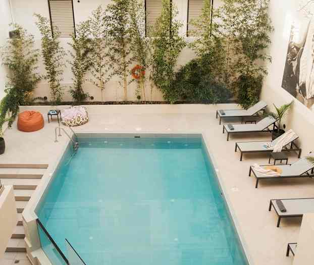 Uima-allas, jonka ympärillä on aurinkotuoleja ja kasvillisuutta. (Tekoälyn luoma teksti)