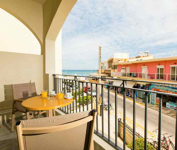 Parveke, jolla pöytä ja tuolit, näkymä kadulle ja merelle. (Tekoälyn luoma teksti)