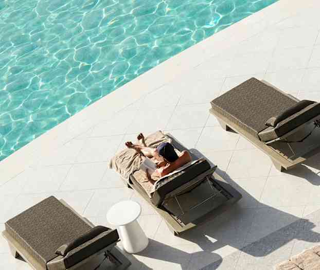 Henkilö rentoutuu aurinkotuolilla uima-altaan vieressä. (Tekoälyn luoma teksti)