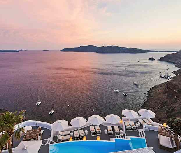 Näkymä rannasta ja merelle auringonlaskun aikaan. Etualalla on uima-allas ja valkoisia aurinkotuoleja varjoilla. (Tekoälyn luoma teksti)