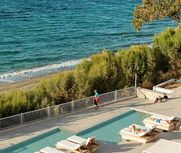 Ulkouima-allas aurinkotuoleineen hiekkarannan ja meren edessä. (Tekoälyn luoma teksti)