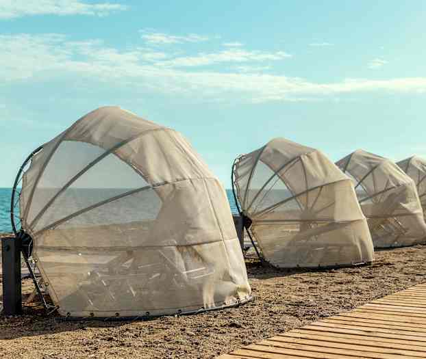 Suojatut aurinkotuolit rannalla lähellä merta. (Tekoälyn luoma teksti)