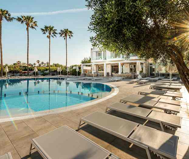 Ulkouima-allas aurinkotuoleilla ja palmuja taustalla. (Tekoälyn luoma teksti)