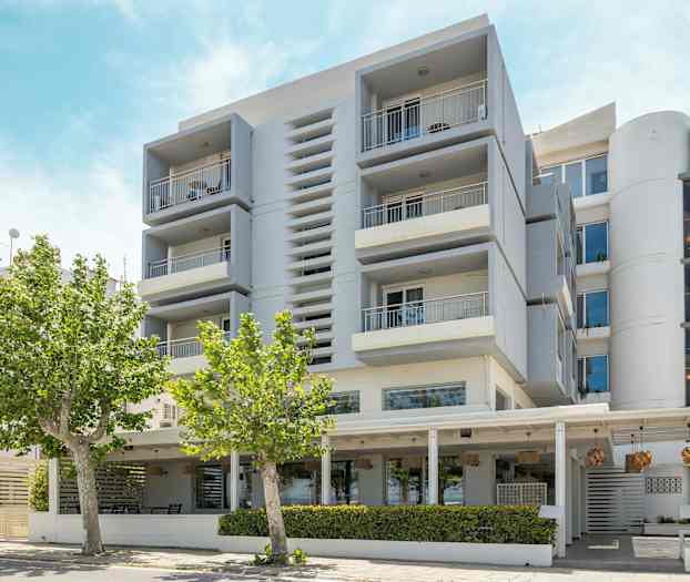 Moderni rakennus parvekkeineen ja puita etualalla. (Tekoälyn luoma teksti)