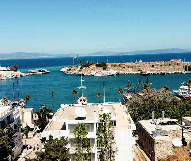 Näkymä satama-alueelle, jossa on veneitä ja historiallinen rakennus rannalla. (Tekoälyn luoma teksti)