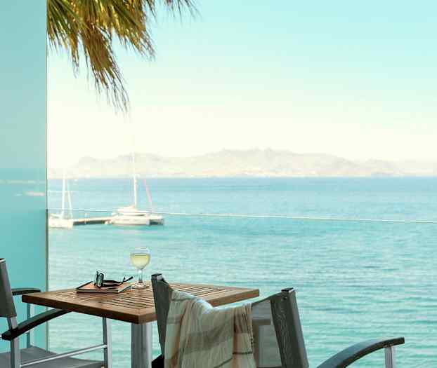 Näkymä merelle parvekkeelta, jossa on pöytä ja tuolit. (Tekoälyn luoma teksti)