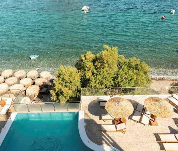 Uima-allasalue aurinkotuoleilla ja aurinkovarjoilla lähellä rantaa ja merta. (Tekoälyn luoma teksti)