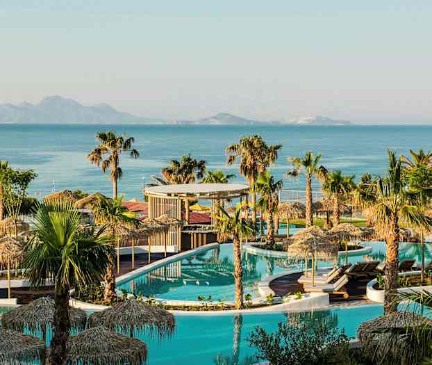 Kuva uima-allasalueesta, jossa on palmuja, aurinkovarjoja ja taustalla meri. (Tekoälyn luoma teksti)