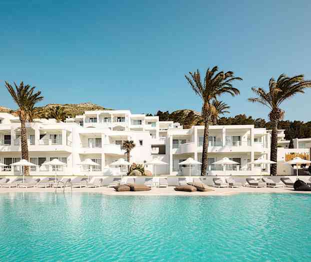 Valkoinen rakennus, jossa parvekkeet, uima-allas ja palmuja. (Tekoälyn luoma teksti)