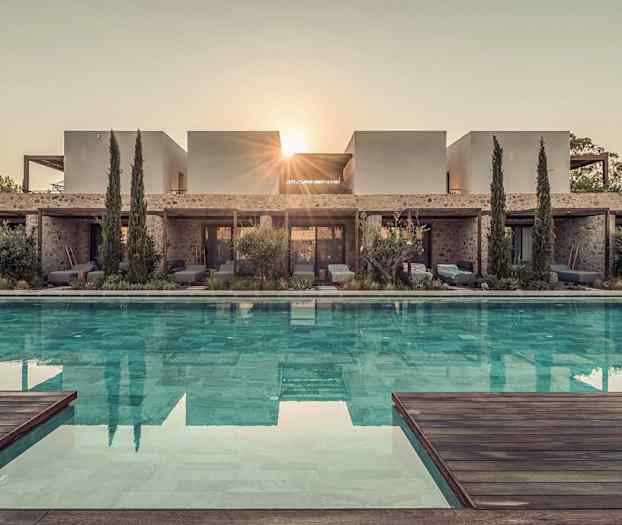 Kuva modernista villasta, jonka edessä on uima-allas, ympärillä kasvillisuutta ja puita, auringon säteiden näkyessä rakennuksen takana. (Tekoälyn luoma teksti)