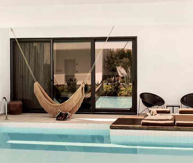 Kuva uima-altaasta, jossa on riippumatto ja aurinkotuoleja reunalla. (Tekoälyn luoma teksti)