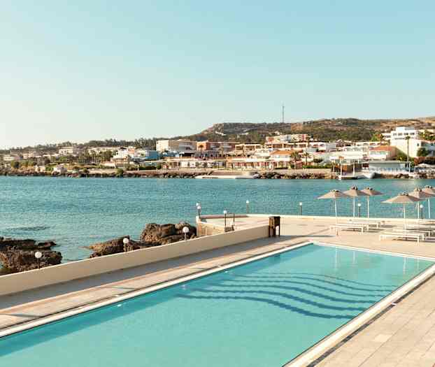 Kuva uima-altaasta, josta on näkymä merelle ja rantakaupunkiin. (Tekoälyn luoma teksti)