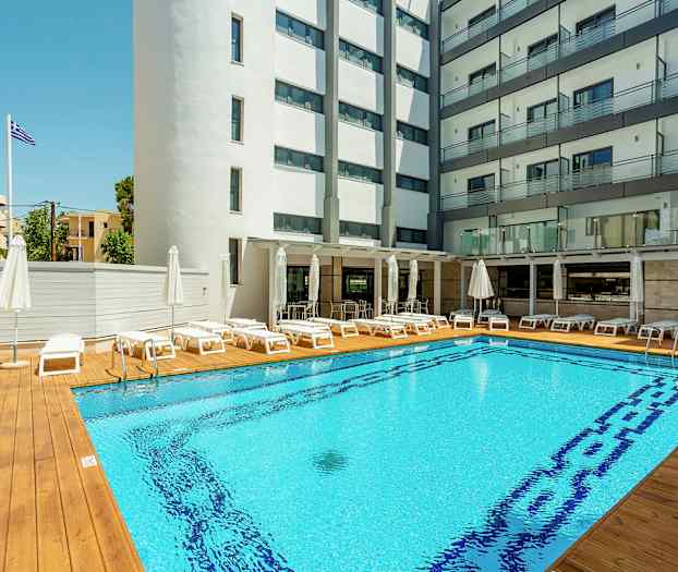 Hotellin uima-allas aurinkotuoleilla ja varjoilla, ympäröitynä rakennuksilla. (Tekoälyn luoma teksti)