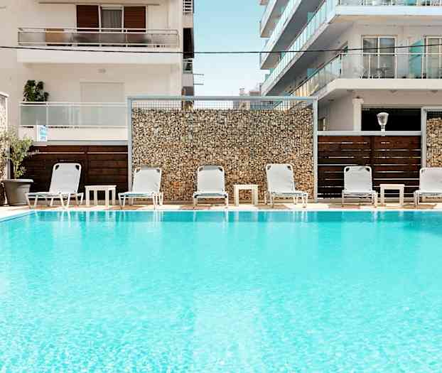 Uima-allas, jonka edessä aurinkotuoleja ja pöytiä rakennusten edessä. (Tekoälyn luoma teksti)