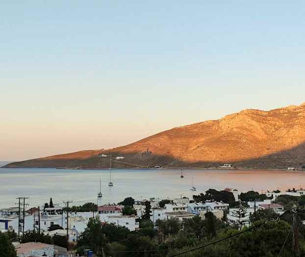 Rantakaupunki, jossa purjeveneitä ja vuoria taustalla. (Tekoälyn luoma teksti)