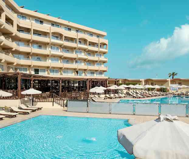 Ulkoallas, jossa aurinkotuoleja ja aurinkovarjoja hotellin vieressä. (Tekoälyn luoma teksti)